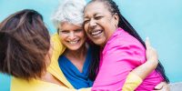 Happy multiracial senior women having fun hugging each other outdoor - Older community lifestyle